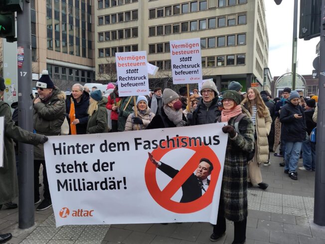Attac Düsseldorf mit Banner "Hinter dem Faschismus steht der Milliardär!