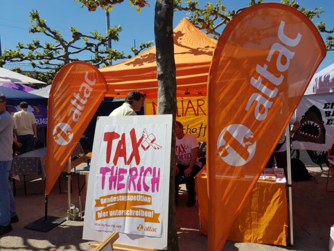Attac-Stand mit Attac-Fahnen und Plakat "Tax the Rich"