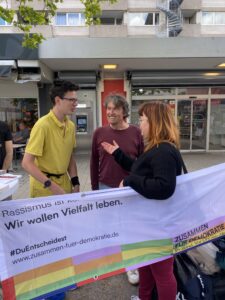 Banner "Wir wollen Vielfalt leben" und Aktive von teilnehmenden Initiativen im Gespräch